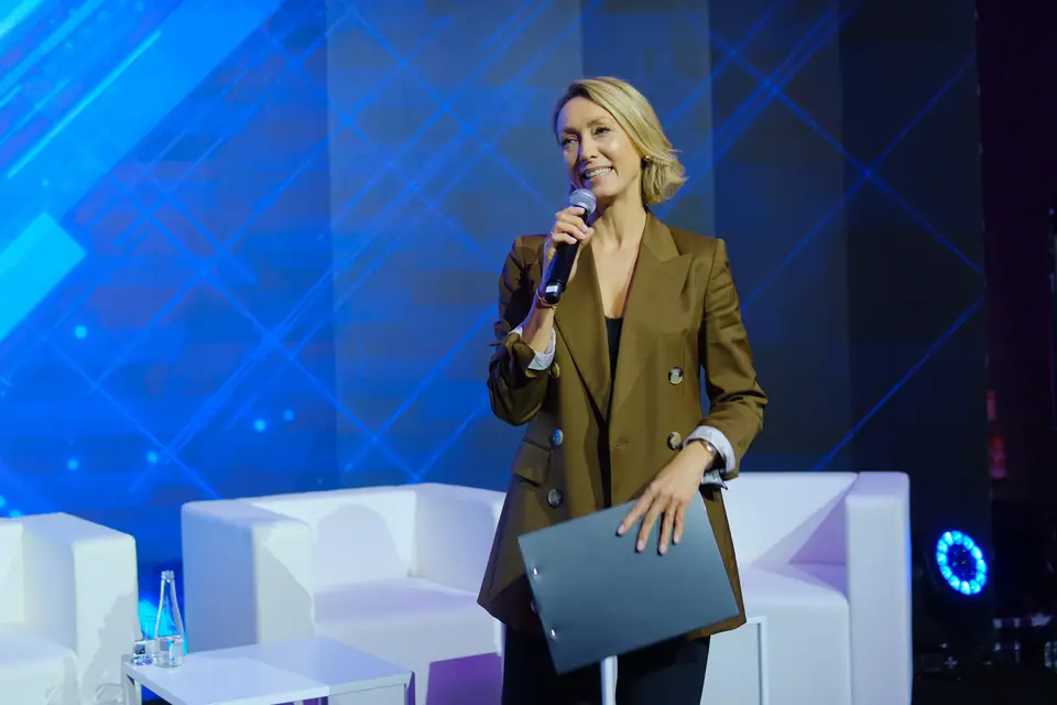 A smiling host on the AI Marketing Innovation Executive Summit 2023 stage