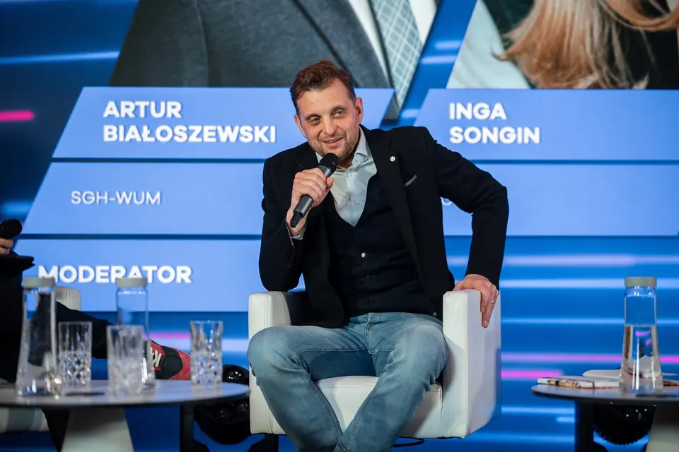 A smiling panellist with a microphone on the EXS 2024 stage