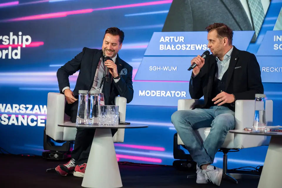 A smiling panellist at the microphone during a discussion on the EXS 2024 stage